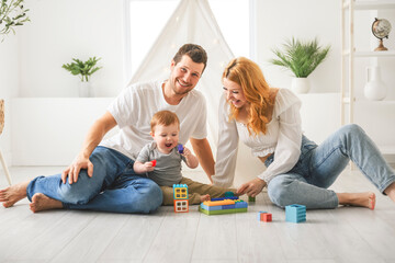 young mother and father with her little son playing at home with toys