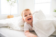 © Louis-Paul Photo - Baby boy in white sunny bedroom. one years child relaxing in bed.