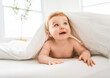 © Louis-Paul Photo - Baby boy in diaper on white sunny bedroom. one years child relaxing in bed.
