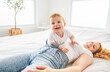 © Louis-Paul Photo - Mother and baby boy on bed, having great moment together on white bedroom