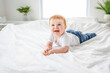 © Louis-Paul Photo - Baby boy in white sunny bedroom. one years child relaxing in bed.