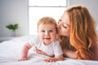 © Louis-Paul Photo - Mother and baby boy on bed, having great moment together on white bedroom