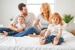 © Louis-Paul Photo - happy family mother, father and children having fun in bed in bedroom at home