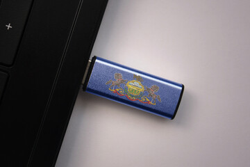 Wall Mural - usb flash drive in notebook computer with the national flag of pennsylvania state on gray background.