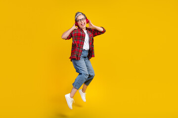 Poster - Full length photo of energetic nice lady jump hands touch headphones empty space isolated on yellow color background