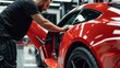 © AlfaSmart - Technician using squeegee to smooth protective film on door panel of luxury sports car