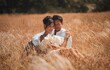 A stunning married couple embraces alidst a golden wheat field at sunset. Perfect romantic-themed
