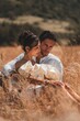 A stunning married couple embraces alidst a golden wheat field at sunset. Perfect romantic-themed
