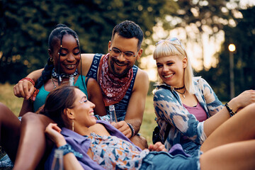 Wall Mural - Happy friends relaxing in nature while attending open air music concert in summer.