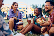 Happy black woman and her friends enjoying in beer and burgers during summer music festival.