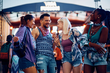 Cheerful friends having fun while dancing during open air music concert in summer.