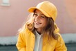 Portrait of a beautiful smiling girl in a yellow cap and a yellow raincoat