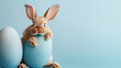 Adorable Easter bunny rabbit peeping and hiding behind Easter egg on blue background