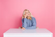 Photo of upset unsure woman wear pullover sitting office looking empty space isolated pink color background