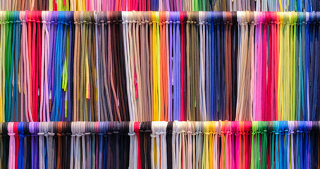 Leinwandbilder - A row of colorful strings laces are displayed in a store. The colors are bright and vibrant, creating a cheerful and lively atmosphere. The strings are arranged in a way that showcases their variety