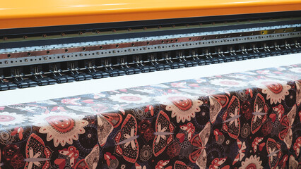 Poster - A machine is printing a pattern on a piece of fabric. The pattern is floral and has a mix of colors.