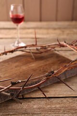 Wall Mural - Crown of thorns and glass with wine on wooden table, selective focus