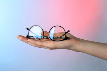 Canvas Print - Woman holding glasses with black frame on color background, closeup