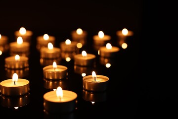 Wall Mural - Burning candles on mirror surface in darkness, closeup. Space for text