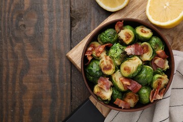 Wall Mural - Delicious roasted Brussels sprouts, bacon and lemon on wooden table, top view. Space for text