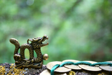 Wall Mural - A metal dragon figurine and Chinese coins. Amulets and talismans.