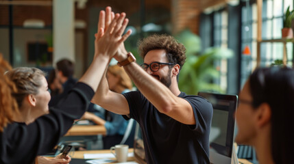 Sticker - Young man with an afro hairstyle and glasses is smiling and giving a high-five in a casual office or coworking space environment.