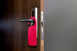 Wooden door with empty Red Tag hanging on the handle. Ideal template for mockup do not disturb sign.