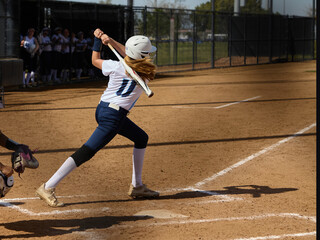 Wall Mural - Young female Softball player playing youth sports. Swinging bat.