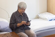 © Anna Berkut/Stocksy - senior woman using mobile phone smartphone, sitting on the bed at home