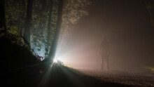 A Man Looking At A Mysterious Light In A Forest