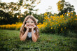 © Maria Manco/Stocksy - Preteen smiles at camera in wildflower field