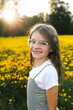 © Maria Manco/Stocksy - Preteen smiles at camera in wildflower field