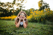 © Maria Manco/Stocksy - Preteen smiles at camera in wildflower field