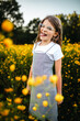 © Maria Manco/Stocksy - Preteen smiles at camera in wildflower field