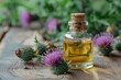 A bottle of tincture or essential oil and flowers of thistle on a wooden background