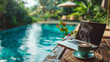 © CozyDigital - Photo of laptop and cup of coffee standing on table with swimming pool on the background. The concept of remote work and combining leisure with work