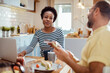 © Davor - Diverse young couple using credit card at the kitchen table