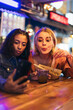 © Pedro Merino/Stocksy - Girlfriends taking selfies while having a date at a street market