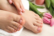 Woman with neat toenails after pedicure procedure on white wooden floor, closeup