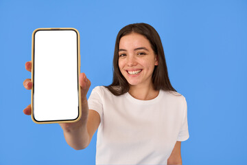Happy young gen z Latin girl shopper girl student holding smartphone using mobile cell phone showing big mockup screen advertising new sale app promo on cellphone app isolated on blue background.
