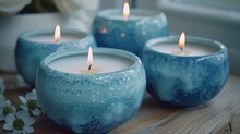 A Group Of Three Blue Candles Sitting On Top Of A Table Next To A White Flower On Top Of A Wooden Table.