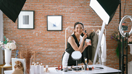 Wall Mural - Woman influencer shoot live streaming vlog video review vivancy makeup social media or blog. Happy young girl with cosmetics studio lighting for marketing recording session broadcasting online.