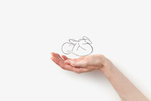 Close up of female hand with line drawn baby on white background