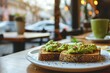 Toast bread with avocado puree on table on blurred cafe background. Vegetarian food.