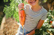 © Maria Manco/Stocksy - Child holds orange carrot