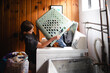 © Maria Manco/Stocksy - Tween loads washing machine with laundry
