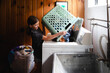 © Maria Manco/Stocksy - Tween loads washing machine with laundry