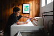 © Maria Manco/Stocksy - Tween loads washing machine with laundry