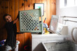 © Maria Manco/Stocksy - Tween loads washing machine with laundry