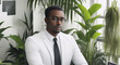 © Volodymyr - Black intelligent man in glasses and business white suit in office with indoor plants